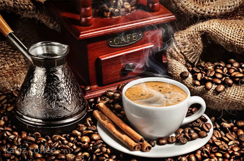 یک فنجان قهوه شیرین و دانه های قهوه و قهوه جوش