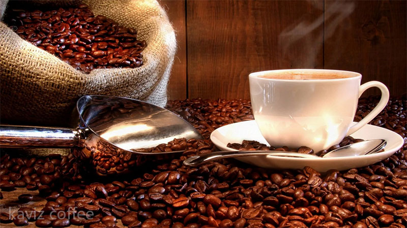 دانه های قهوه در گونی با یک فنجان قهوه